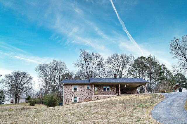 exterior space featuring a chimney, a front lawn, and brick siding