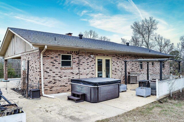 rear view of property with a patio, brick siding, and a hot tub