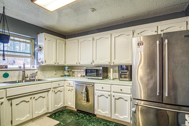 kitchen with tasteful backsplash, decorative light fixtures, stainless steel appliances, light countertops, and a sink