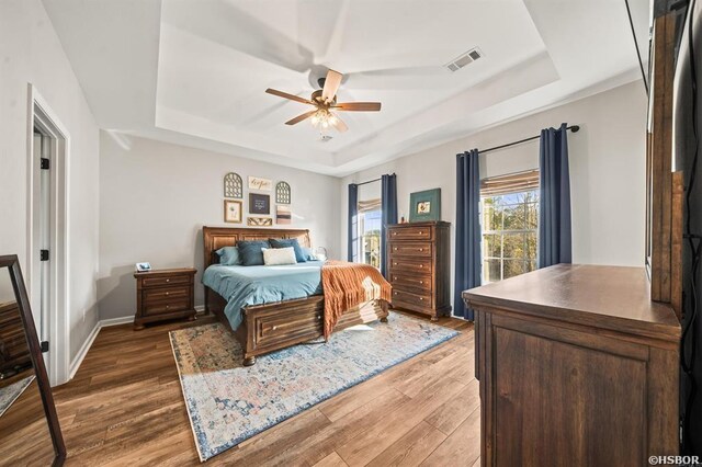 bedroom featuring dark wood-style floors, a raised ceiling, and visible vents