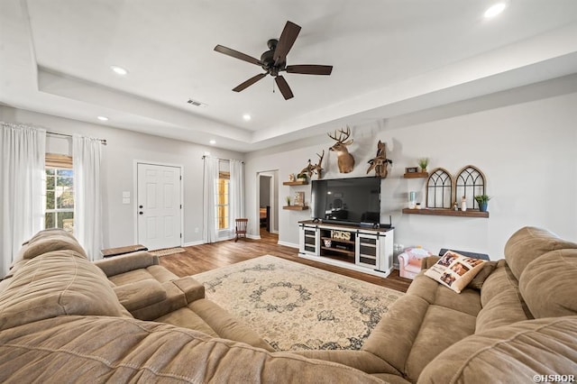 living room with visible vents, a ceiling fan, wood finished floors, a tray ceiling, and recessed lighting