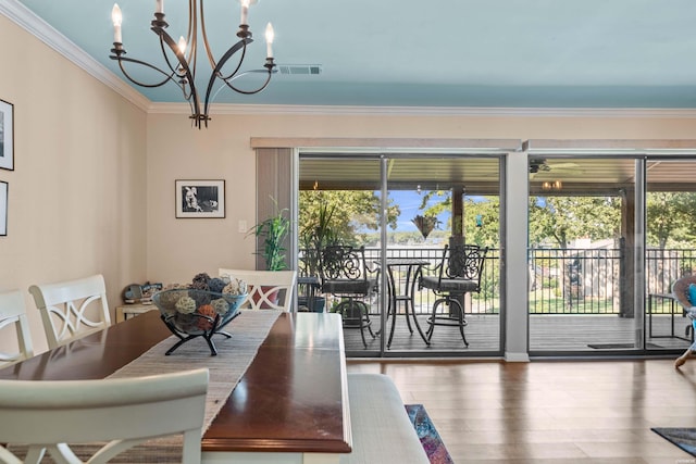 dining area featuring an inviting chandelier, crown molding, visible vents, and wood finished floors