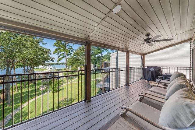 wooden deck with a ceiling fan, a water view, a yard, and area for grilling