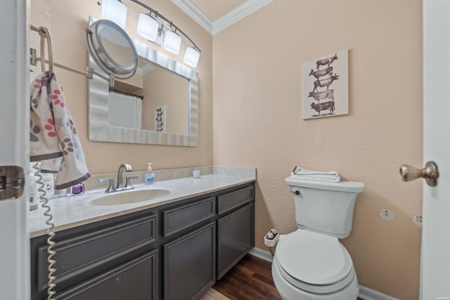 bathroom with toilet, wood finished floors, vanity, and crown molding