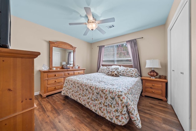 bedroom with a ceiling fan, visible vents, dark wood finished floors, and a closet