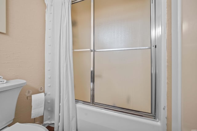 bathroom with combined bath / shower with glass door and toilet