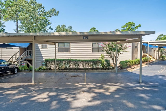 view of front of home featuring covered and uncovered parking and stairs