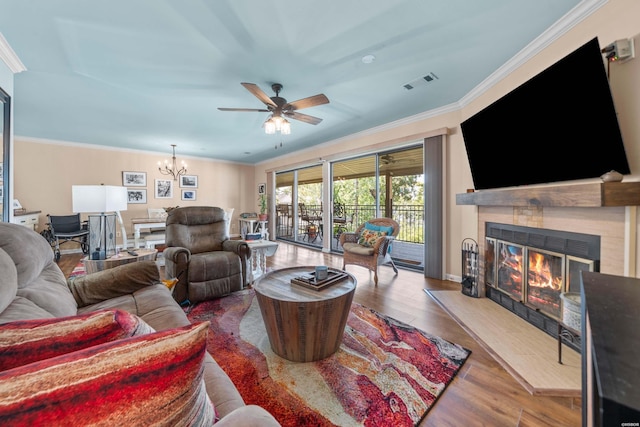 living room featuring visible vents, ornamental molding, wood finished floors, and a glass covered fireplace