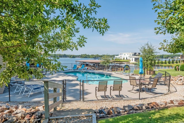 community pool with a water view, a gate, fence, and a patio