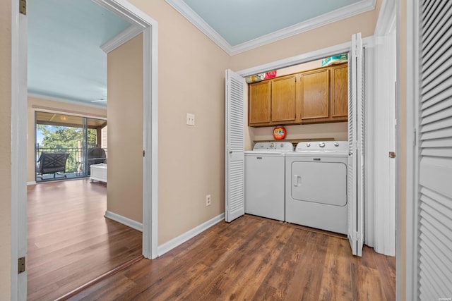 laundry room with dark wood-type flooring, ornamental molding, washer and clothes dryer, and cabinet space