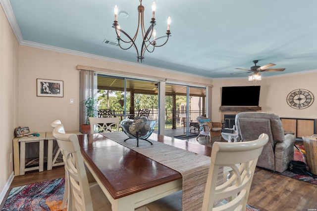 dining room with dark wood-type flooring, visible vents, ornamental molding, and a fireplace