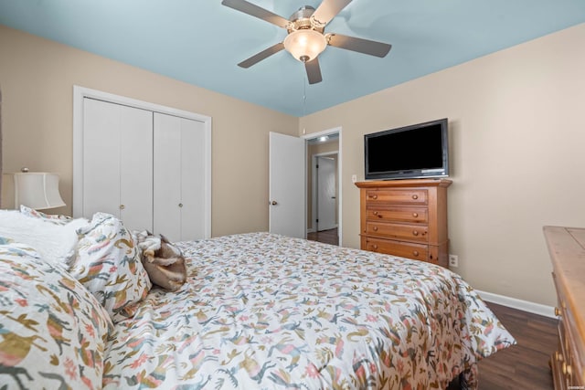 bedroom with dark wood-type flooring, a closet, baseboards, and a ceiling fan