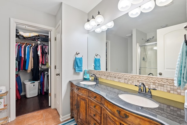 bathroom featuring a spacious closet, backsplash, a sink, and tile patterned floors