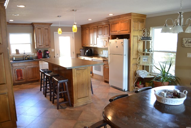 kitchen featuring a center island, pendant lighting, ornamental molding, a sink, and white appliances