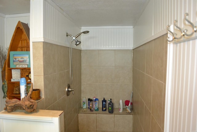 bathroom with a textured ceiling, tiled shower, and tile walls