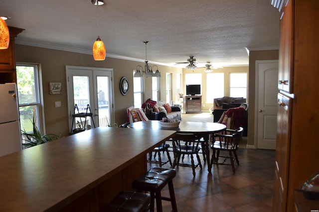 dining room featuring ornamental molding, a textured ceiling, and ceiling fan with notable chandelier