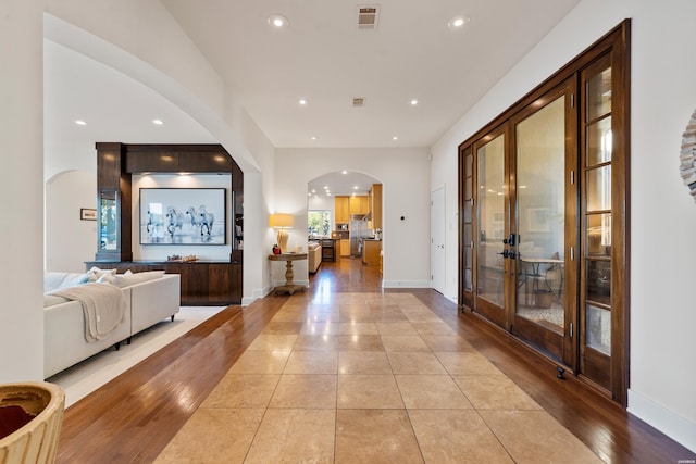 foyer with visible vents, arched walkways, baseboards, light wood-style floors, and recessed lighting