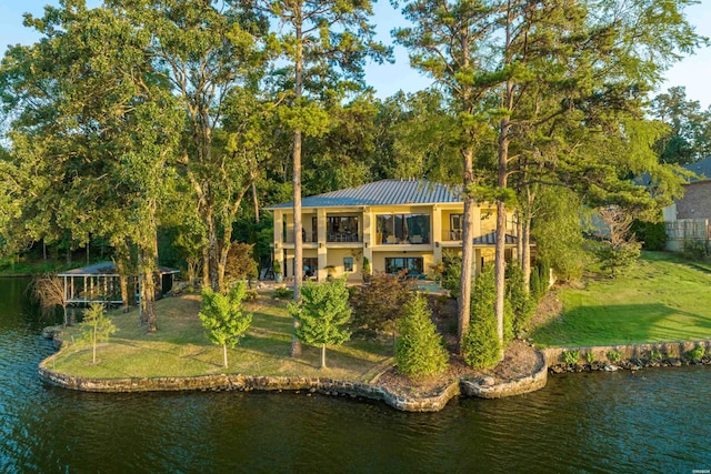 rear view of house featuring a water view, a yard, and stucco siding