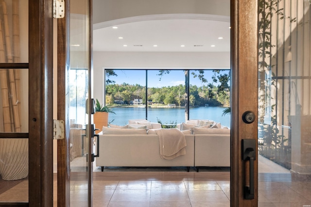 living room with a water view, light tile patterned flooring, arched walkways, and recessed lighting