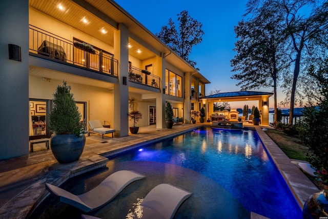 pool at dusk featuring a pool with connected hot tub, a patio area, and a gazebo