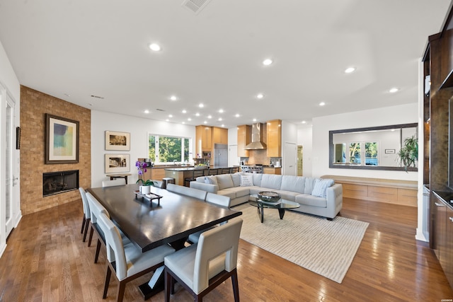 dining area featuring a large fireplace, visible vents, wood finished floors, and recessed lighting