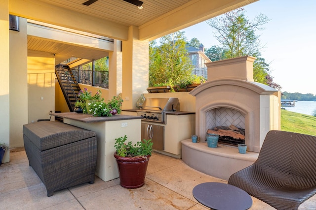 view of patio / terrace with an outdoor kitchen, a water view, a fireplace, stairway, and grilling area