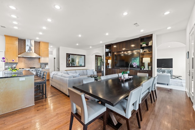 dining room featuring light wood finished floors, visible vents, arched walkways, and recessed lighting