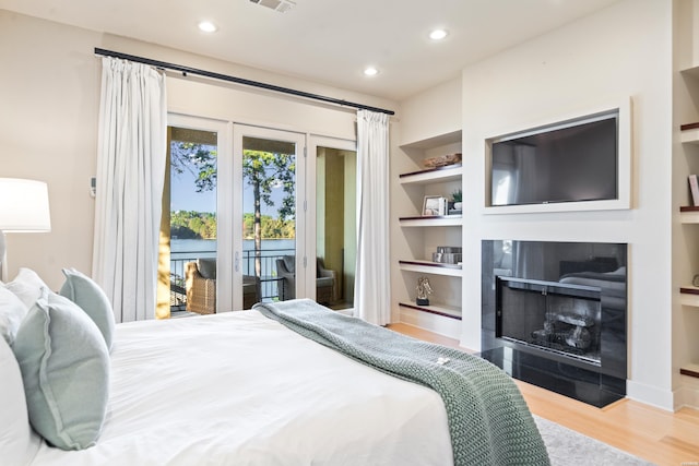 bedroom featuring recessed lighting, wood finished floors, visible vents, access to outside, and a tiled fireplace