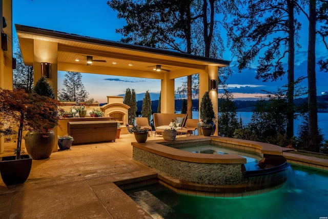 patio terrace at dusk featuring an outdoor fireplace, an outdoor pool, and an in ground hot tub