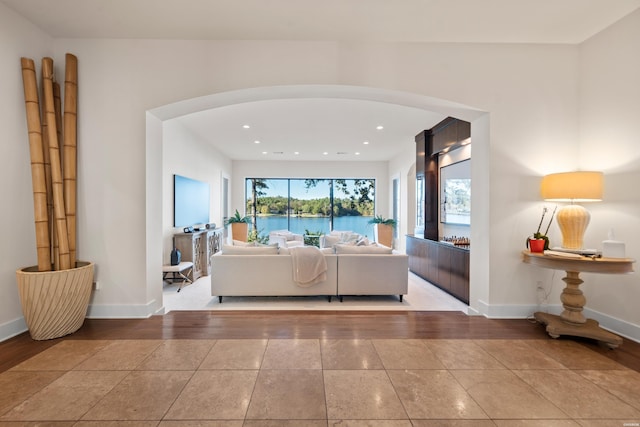 living room with arched walkways, light tile patterned floors, recessed lighting, and baseboards