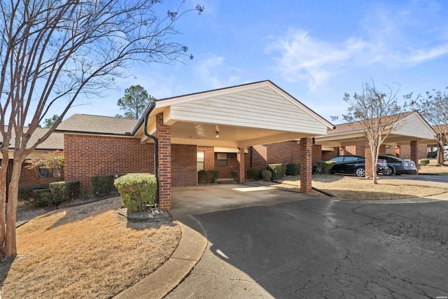 exterior space with a carport, brick siding, and driveway