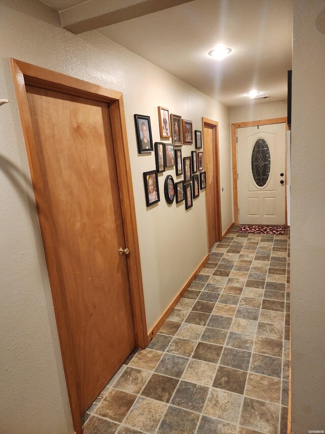 hall featuring stone finish flooring and baseboards