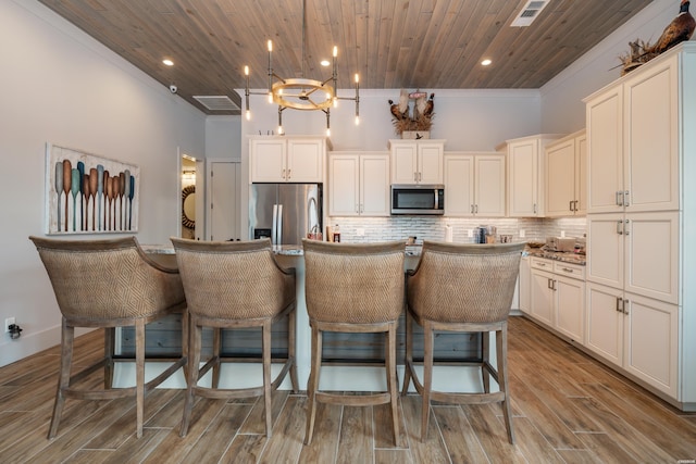 kitchen with wooden ceiling, a kitchen island with sink, appliances with stainless steel finishes, backsplash, and pendant lighting