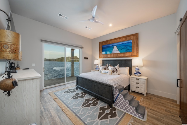 bedroom featuring a water view, access to exterior, visible vents, and wood finished floors