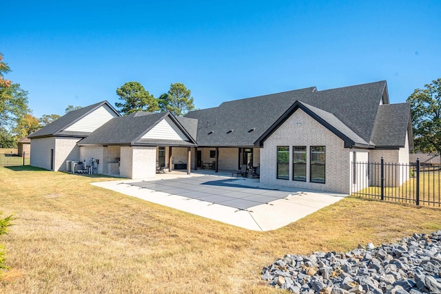 back of property featuring a shingled roof, fence, a yard, a patio area, and brick siding