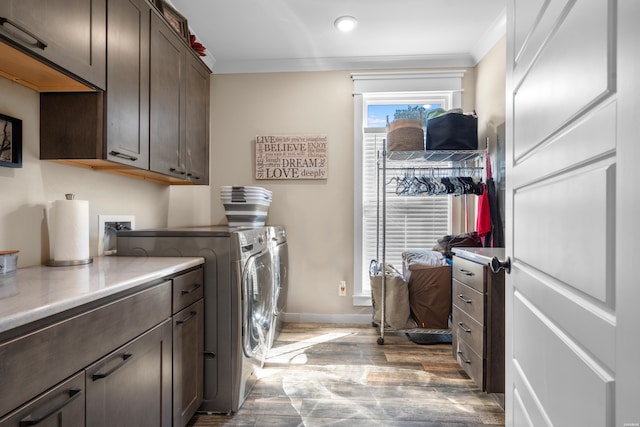 washroom featuring baseboards, ornamental molding, light wood-type flooring, cabinet space, and washer and clothes dryer