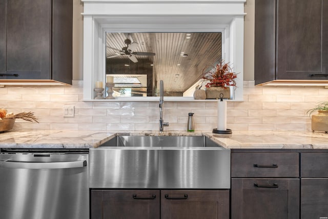 kitchen with tasteful backsplash, light stone counters, dark brown cabinets, stainless steel dishwasher, and a sink