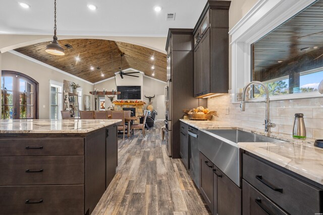 kitchen featuring light stone countertops, hanging light fixtures, ornamental molding, dark brown cabinets, and wood finished floors