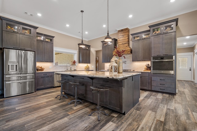 kitchen featuring glass insert cabinets, appliances with stainless steel finishes, dark brown cabinets, and hanging light fixtures