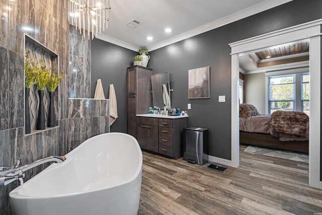 ensuite bathroom with visible vents, ornamental molding, connected bathroom, wood finished floors, and a freestanding tub