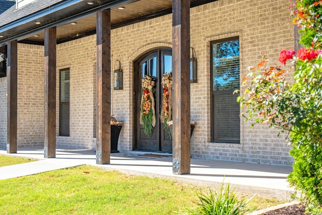 entrance to property with roof with shingles and brick siding