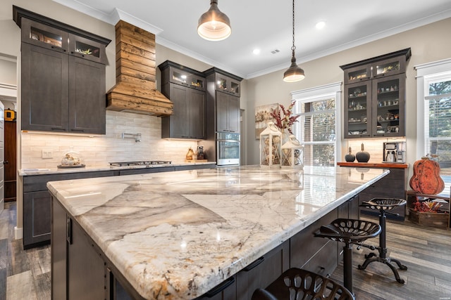 kitchen featuring glass insert cabinets, stainless steel appliances, hanging light fixtures, and light stone counters