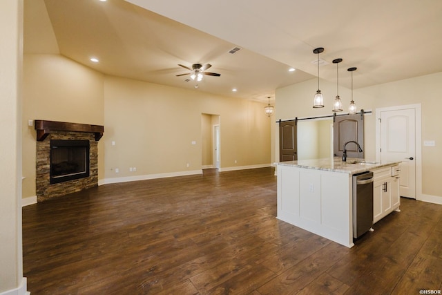 kitchen with a barn door, ceiling fan, open floor plan, dark wood-type flooring, and a sink