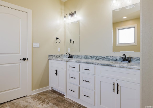 full bathroom with double vanity, baseboards, and a sink