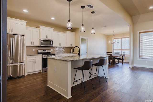 kitchen featuring visible vents, dark wood finished floors, appliances with stainless steel finishes, backsplash, and a sink