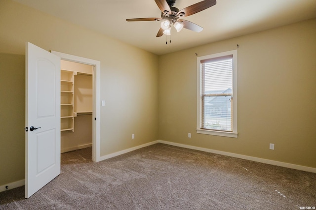 unfurnished bedroom featuring baseboards, ceiling fan, a spacious closet, carpet flooring, and a closet