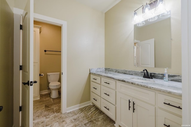 bathroom featuring toilet, vanity, and baseboards