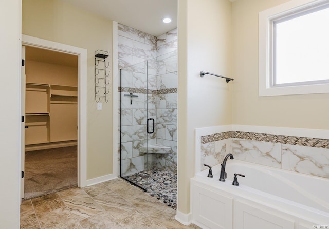 bathroom with a stall shower, baseboards, a walk in closet, and a bath