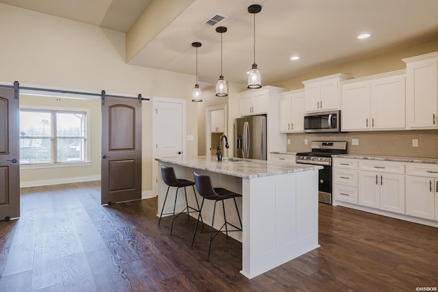 kitchen with visible vents, a barn door, appliances with stainless steel finishes, and white cabinets