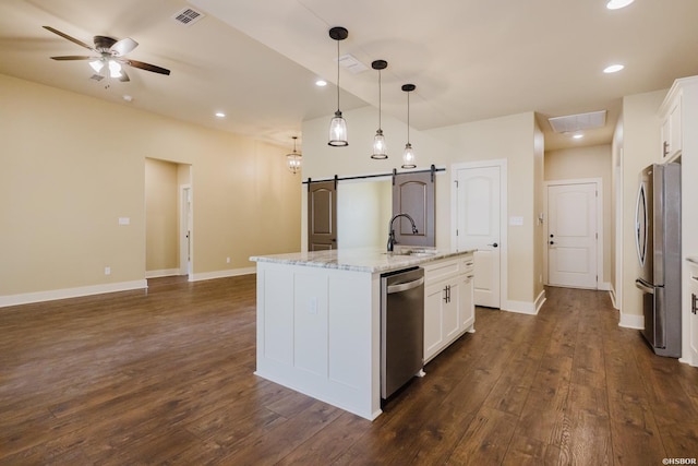 kitchen featuring a barn door, visible vents, white cabinets, stainless steel appliances, and a sink